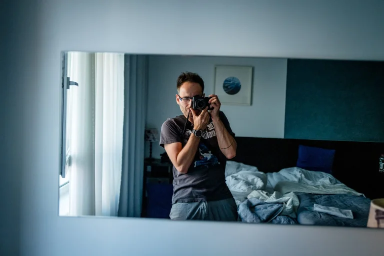Autoportret Bartka Murackiego, na którym widać jego odbicie w lustrze, podczas gdy w ręku trzyma aparat fotograficzny