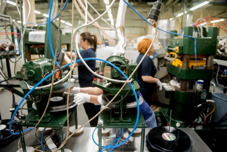 Pracownik kontrolujący jakość płyty winylowej po wyjęciu z formy, ręczna kontrola na etapie produkcji